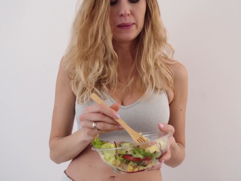 devojka u sportskoj odeći jede salatu