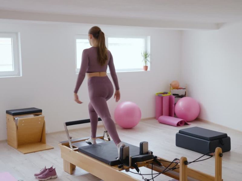 devojka u roze setu za trening na pilates spravi trenira