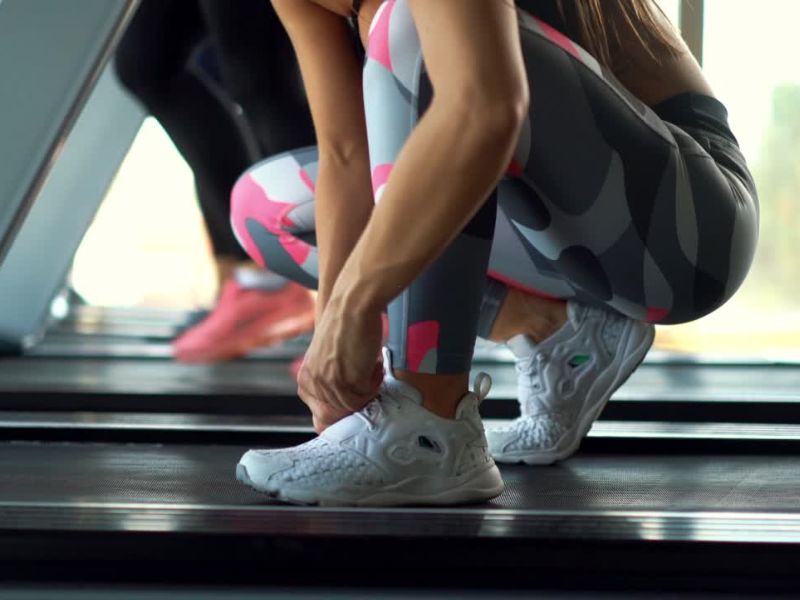 devojka vezuje pertle na traci za trčanje